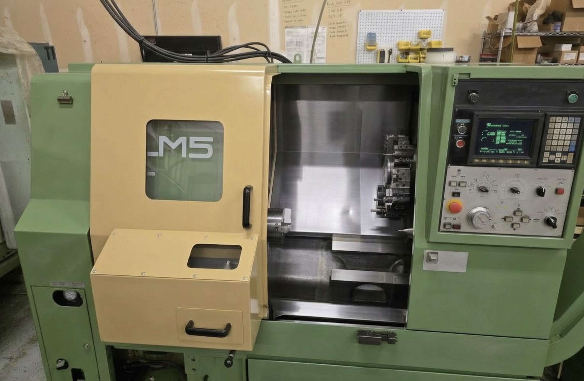 Green CNC lathe with open yellow door showing chuck and turret